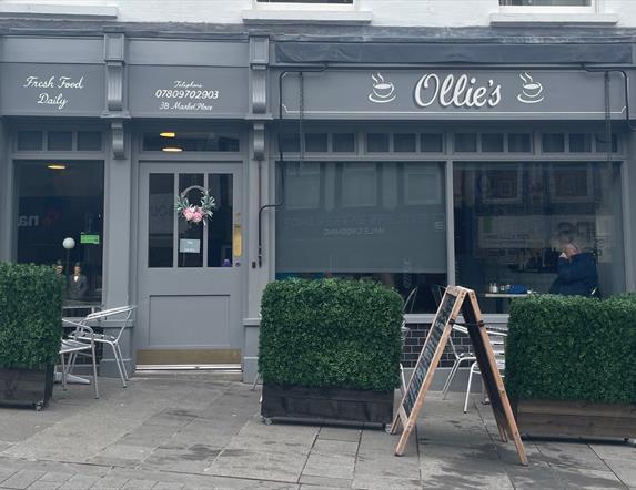 Exterior of Ollie's Bistro, Carrickfergus with grey exterior and outdoor seating area with hedge surround