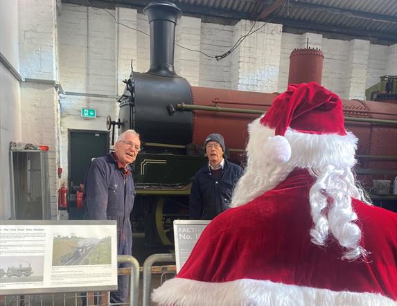 Train with engineers in front of it with Santa looking at them