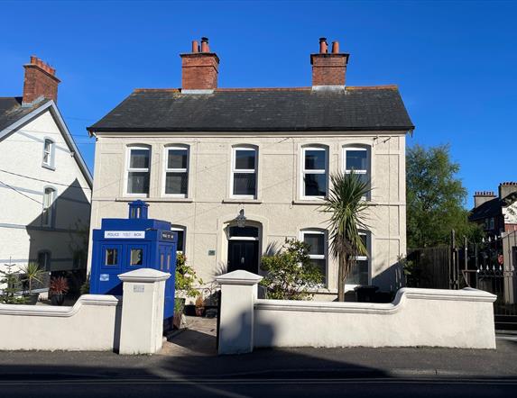White exterior of Sergeants House with old style blue police box as feature in garden