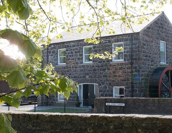 Stone Flax Mill restored self catering - black stone building with water wheel at side of house