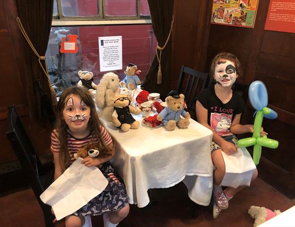 Two little girls sitting at a Teddy Bears Picnic on a train in Whitehead Railway Museum