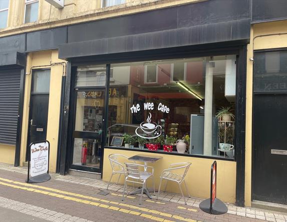 Yellow and Black exterior of the Wee Cafe Larne with name on window and silver outdoor seats