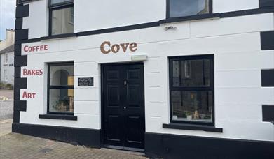 Black and White exterior of Cove Coffee Shop with words painted for Coffee Bakes and Art