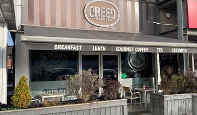 Exterior of Creed Coffee in Larne with outdoor seating area, and grey canopy
