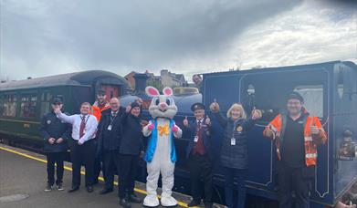 Group of volunteers with Easter Bunny standing outside steam train at Whitehead Railway Museum