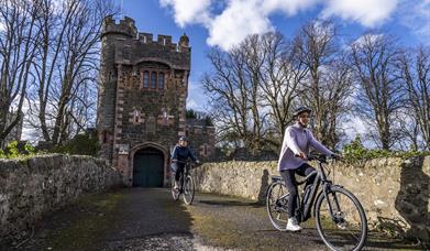 Two cyclists on the bridge that leads to the Barbican Gatelodge