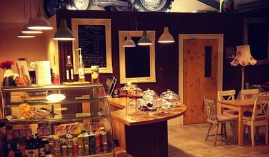 Serving counter in EJ's Country Kitchen in Hillstown, with drinks fridge to the front of the counter and display cases on the counter for scones, bake