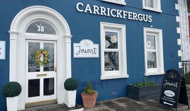 Blue and white exterior of Javart Gift Shop with potted plants