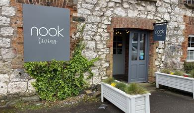 Brick exterior of Nook Living with grey signage and white planter