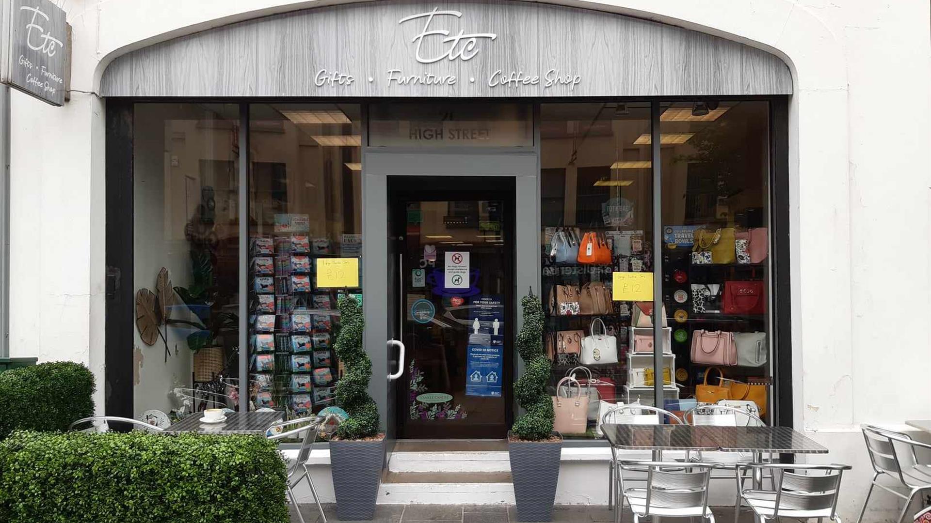 Grey exterior building of ETC Carrickfergus with entrance door and full windows plus outside seating area showing silver tables and chairs plus fake h