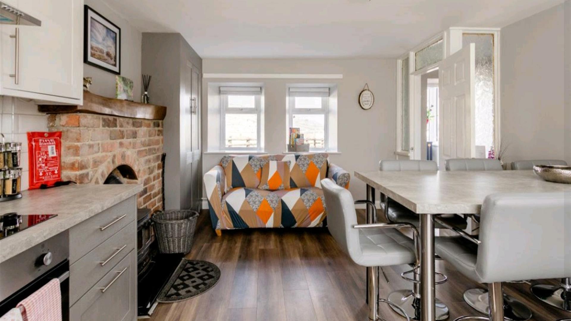 Open plan sitting area with kitchen table front door and a fireplace.