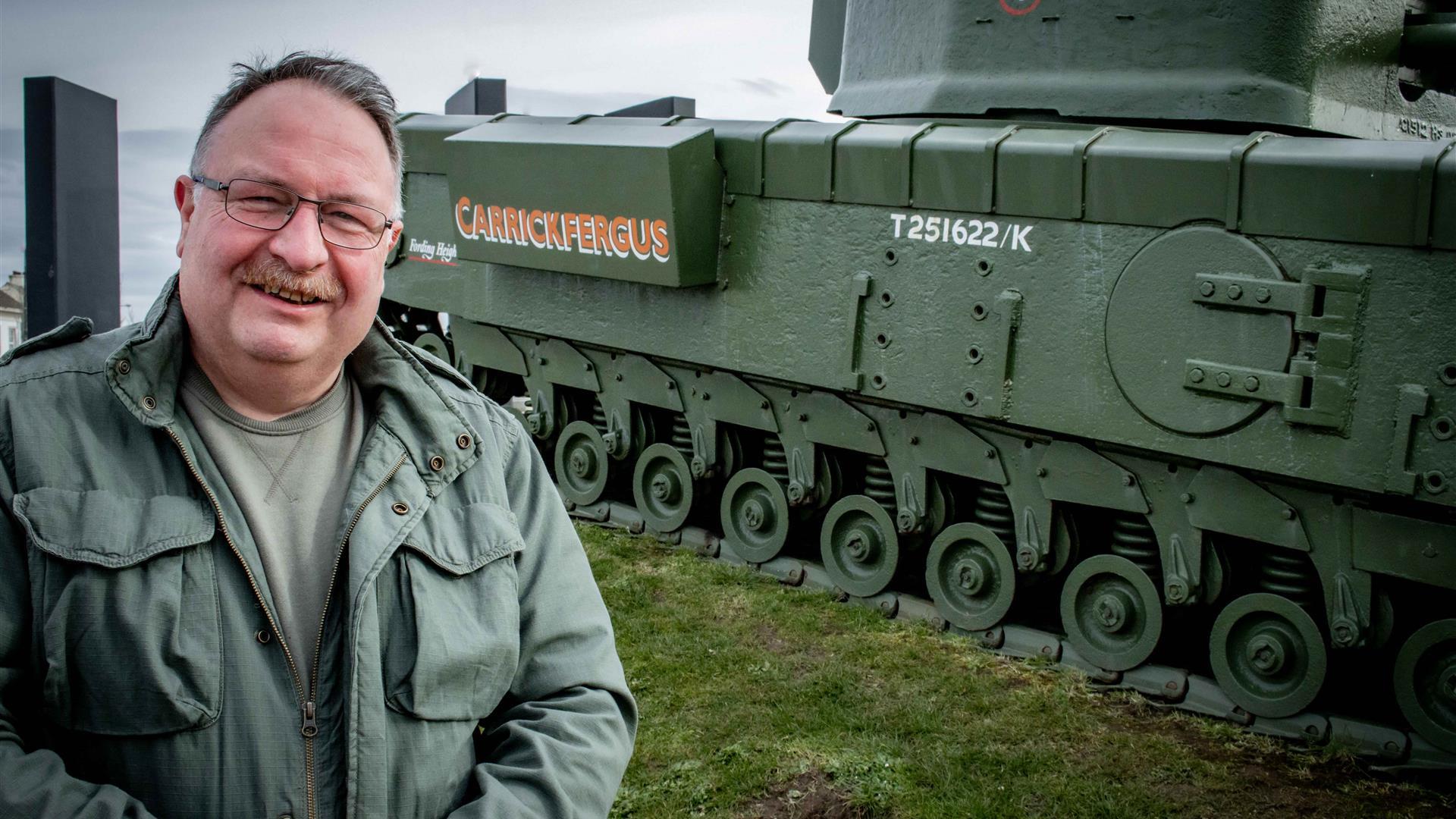 Adrian Hack, tour guide with Lead the Way Tours standing beside the Churchill Tank in Carrickfergus