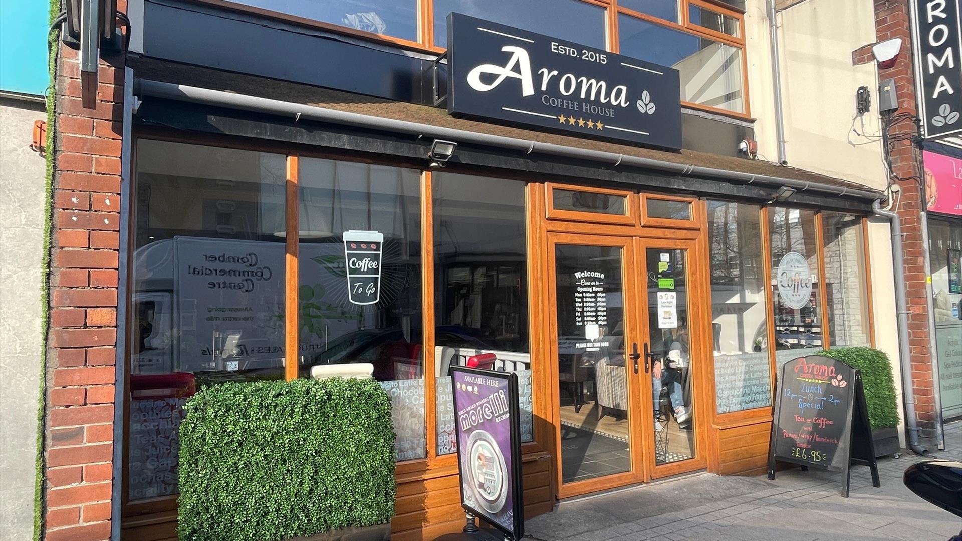 Exterior of Aroma Coffee Shop with wooden door entrance and external signs