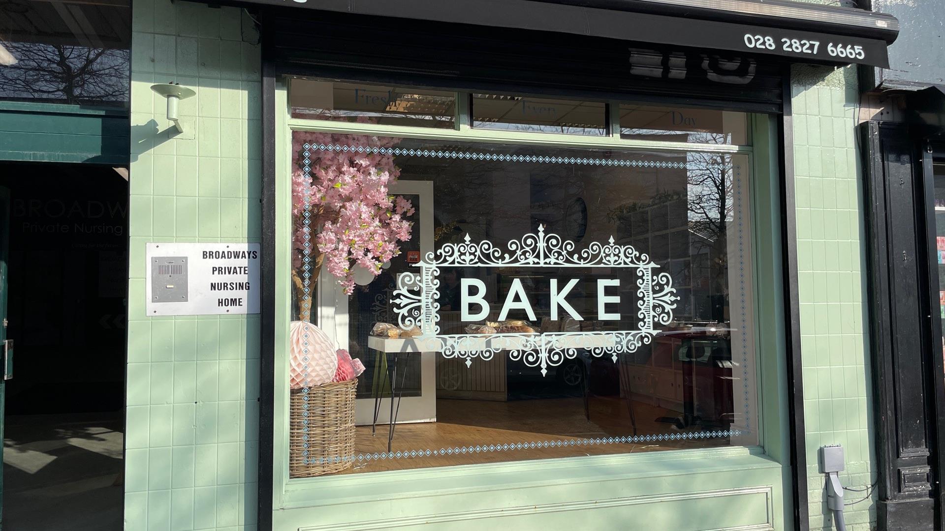 Exterior of Bake bakery in Larne painted light green with black canopy and word BAKE in large window