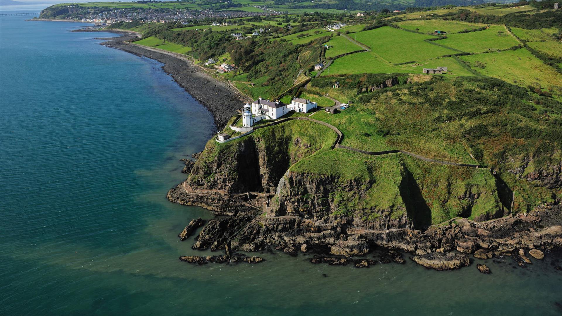 Aerial view of Blackhead Coastal Path and Lighthouse with surrounding countryside