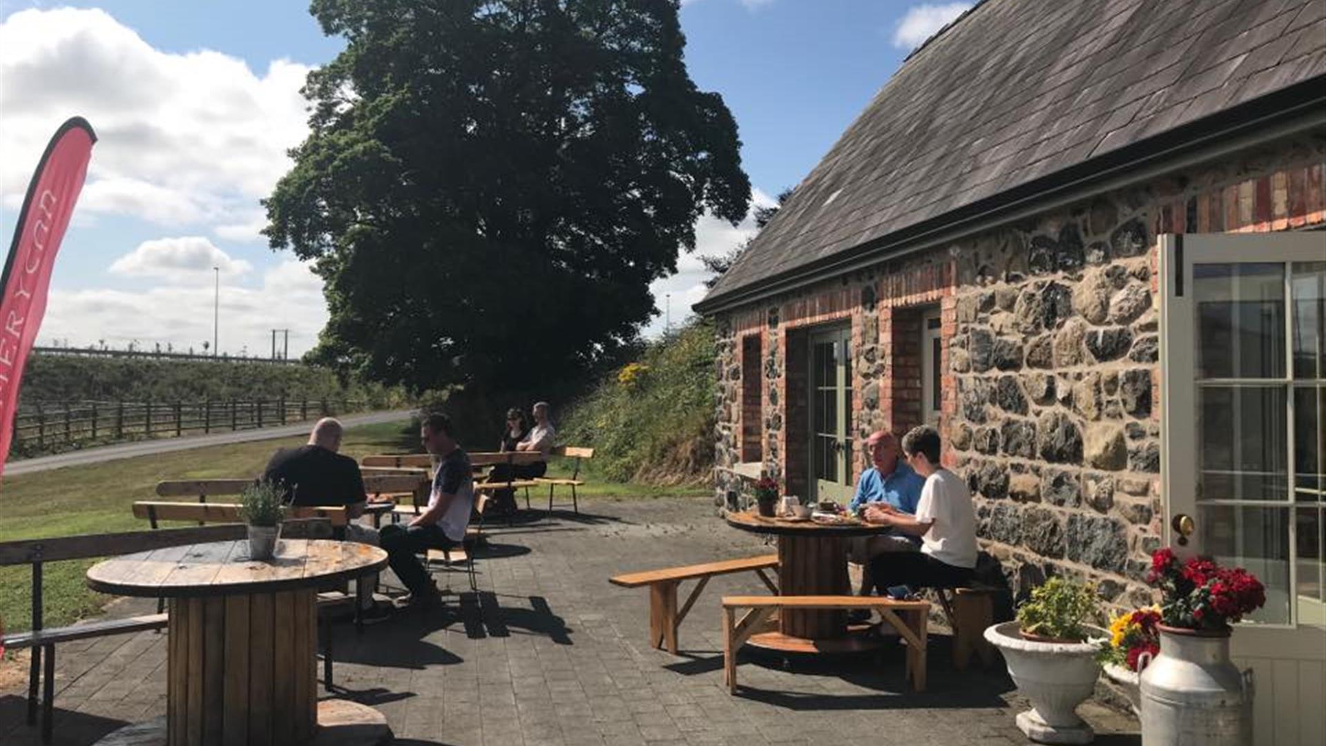 Stone cottage with people dining outside at picnic tables.