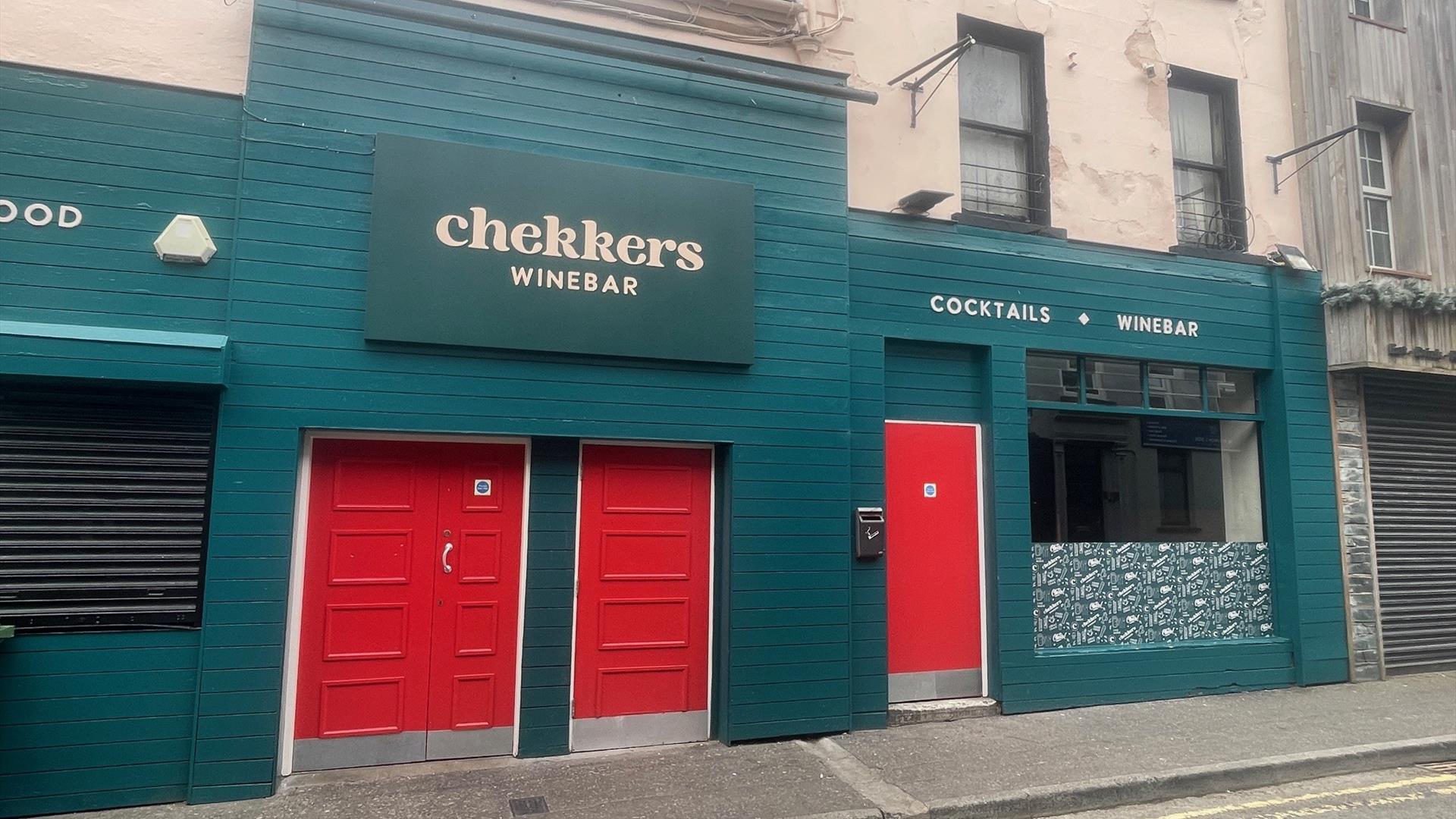 Teal Green exterior of Chekkers Wine Bar with red doors