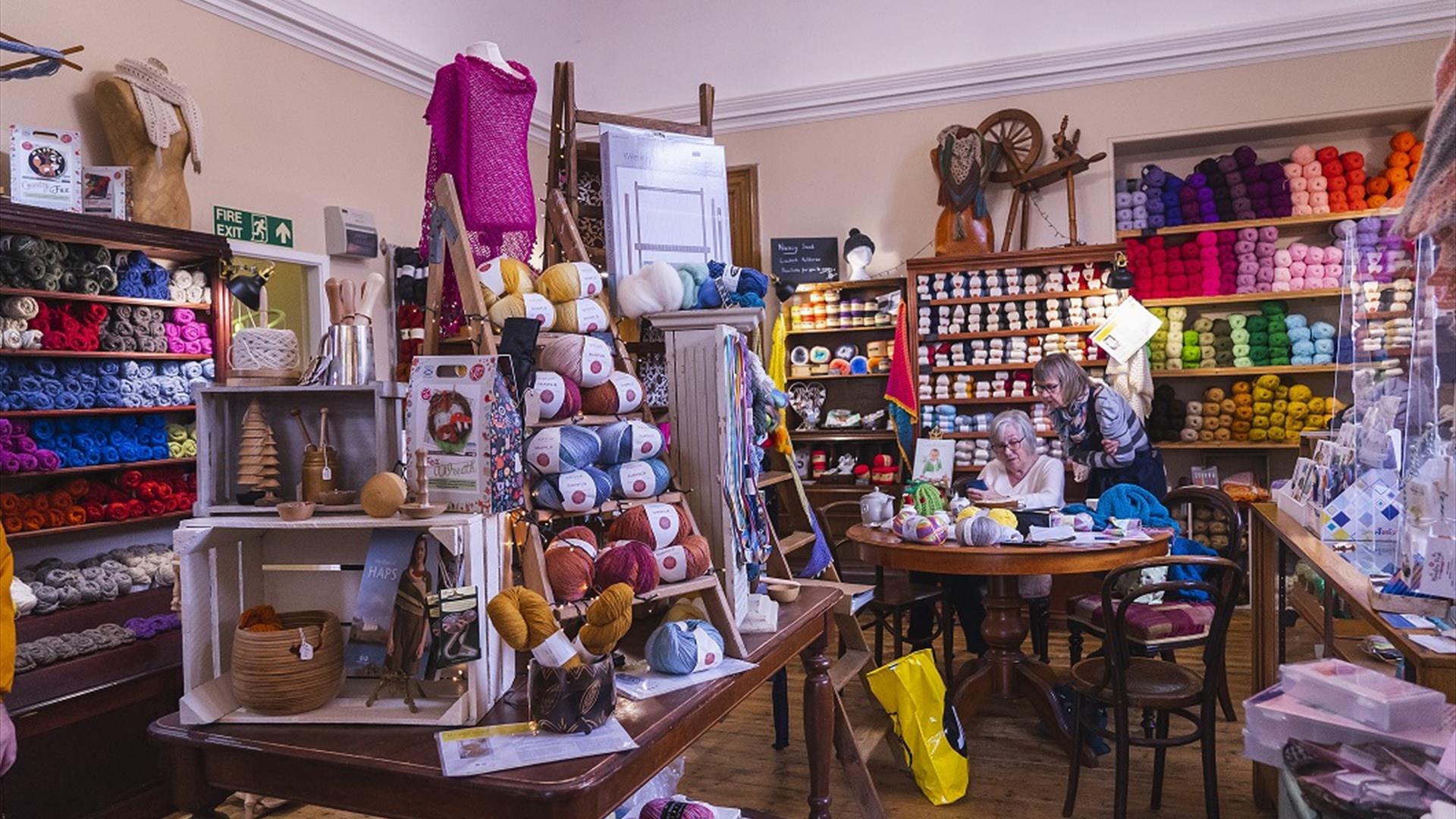 Interior of Lighthouse Yarns with lots of wool displays and people at the crafting table