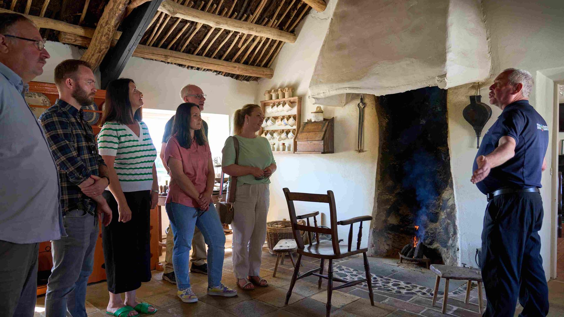 A group of visitors listening to the tour guide inside Andrew Jackson Cottage standing by the fire.