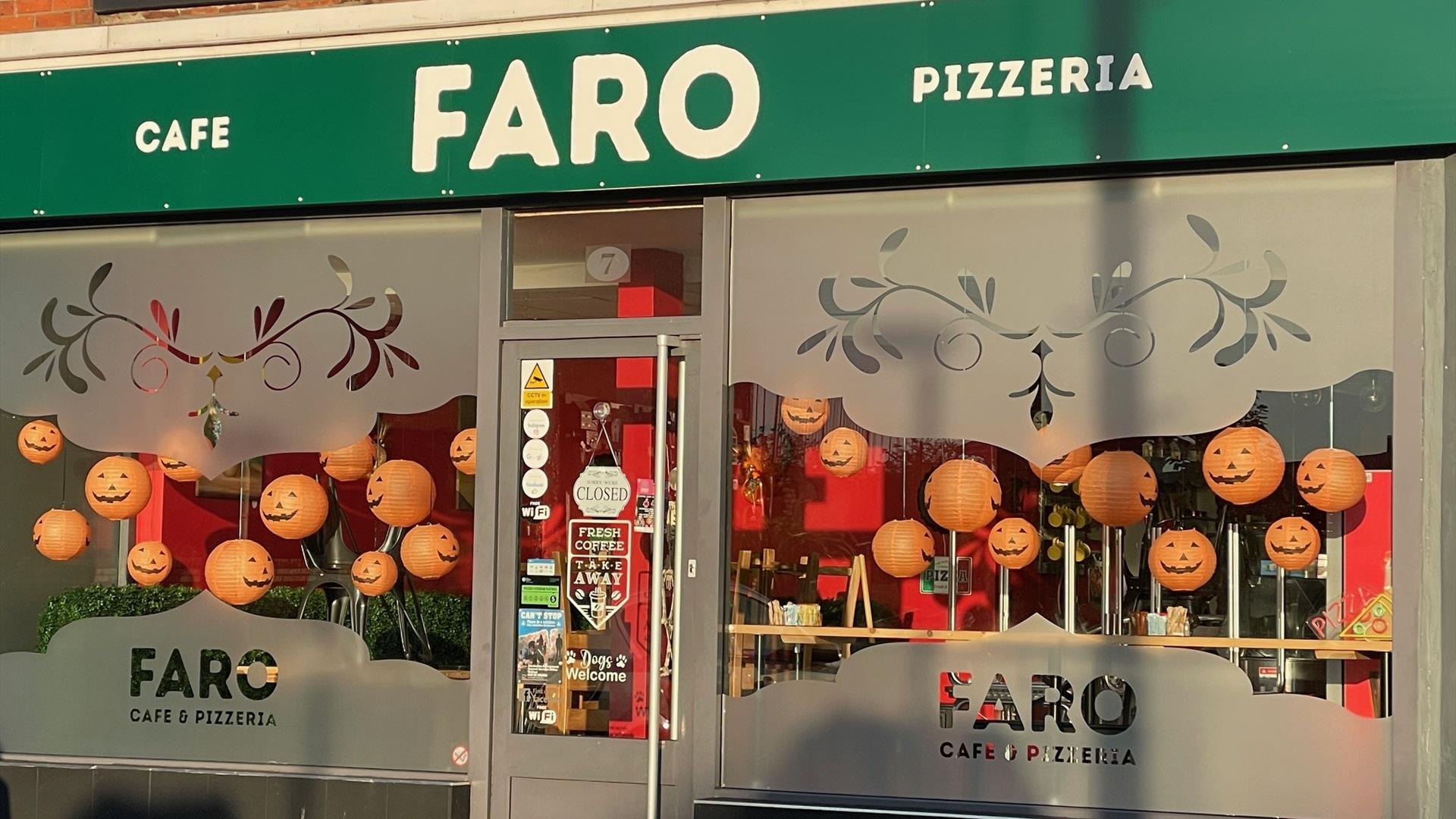 Large windows with FARO branding and green signage - Exterior shop frontage of Faro Cafe & Pizzeria at Halloween