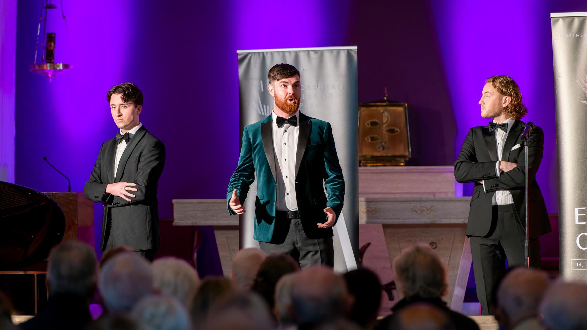 3 individuals in suits performing opera in a church venue