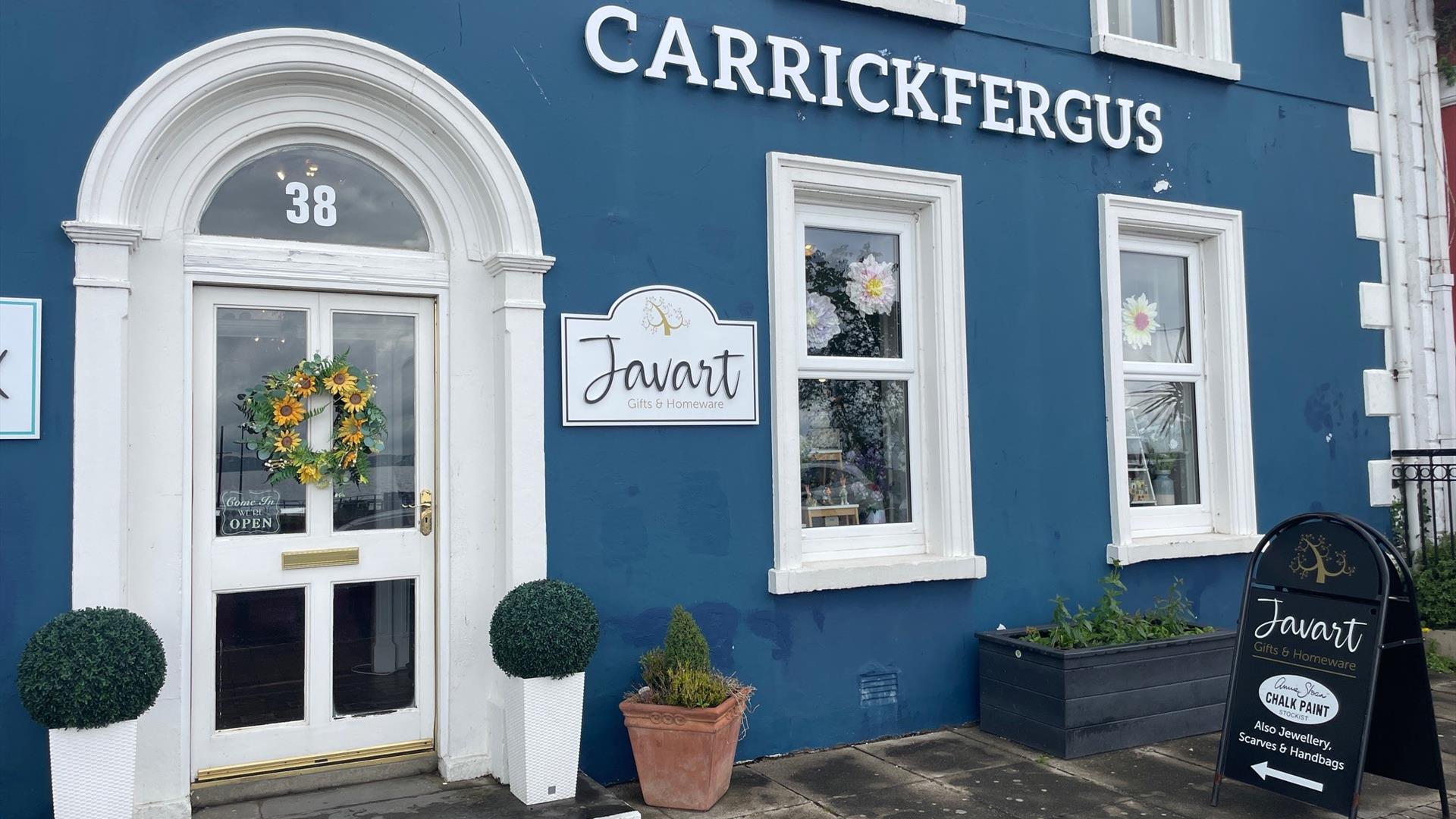 Blue and white exterior of Javart Gift Shop with potted plants