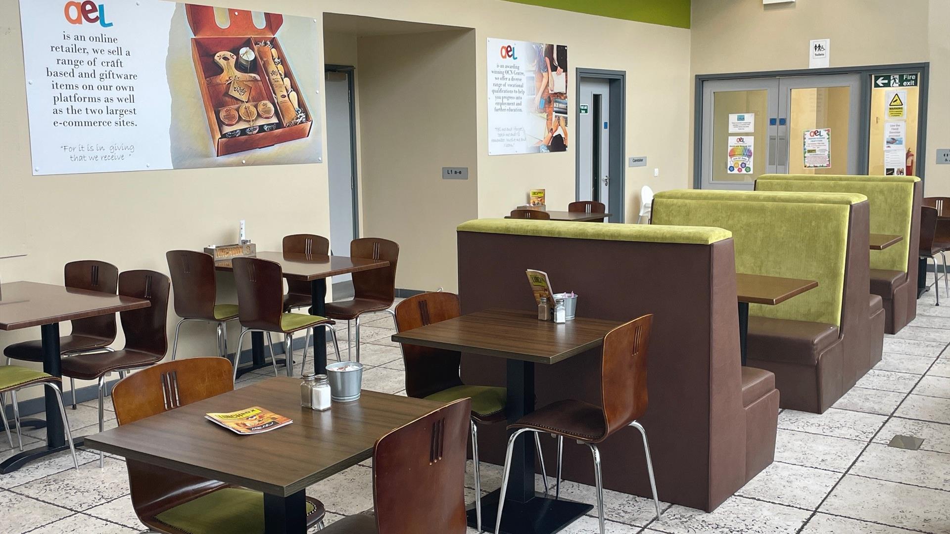 Wooden tables and seats, some with lime green backing within Lunchbox Cafe Larne