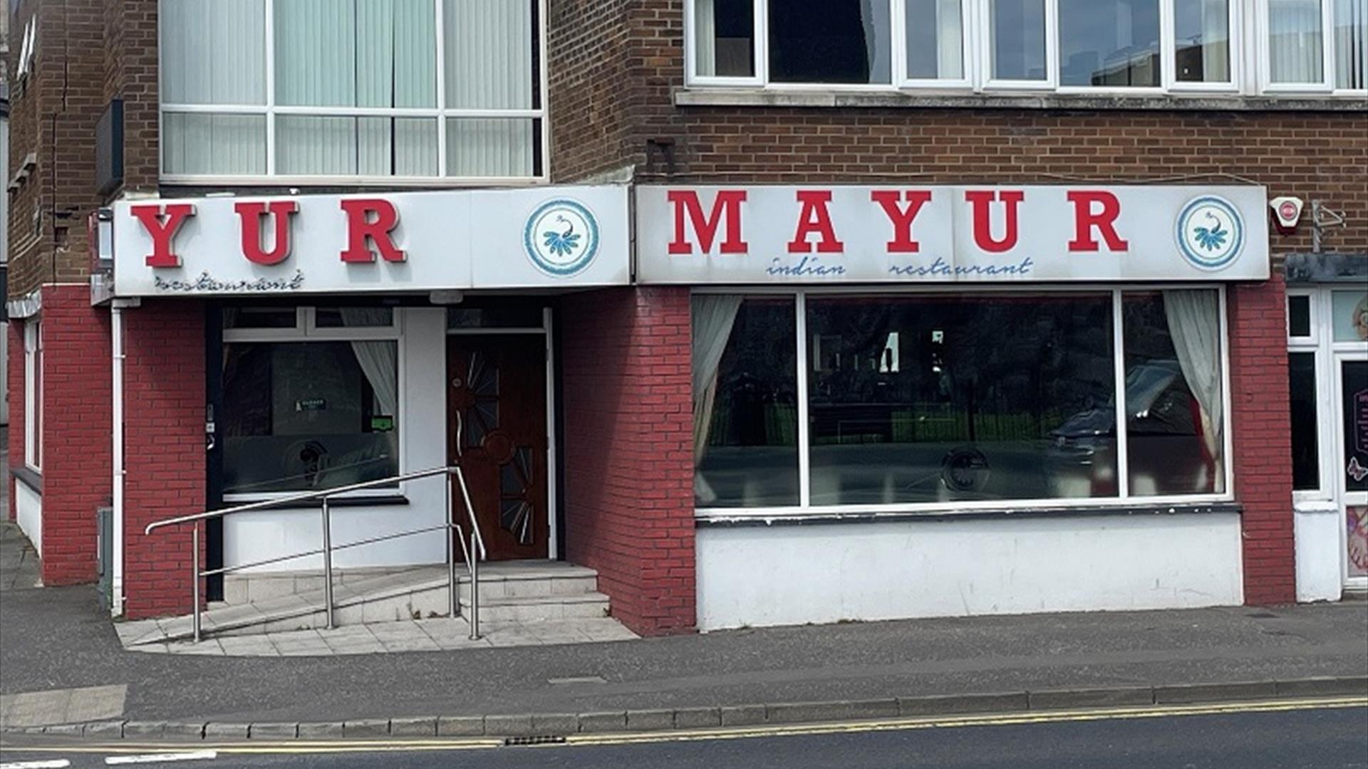 Exterior of Mayur Indian restaurant with sign in red and white, plus whote and red walls