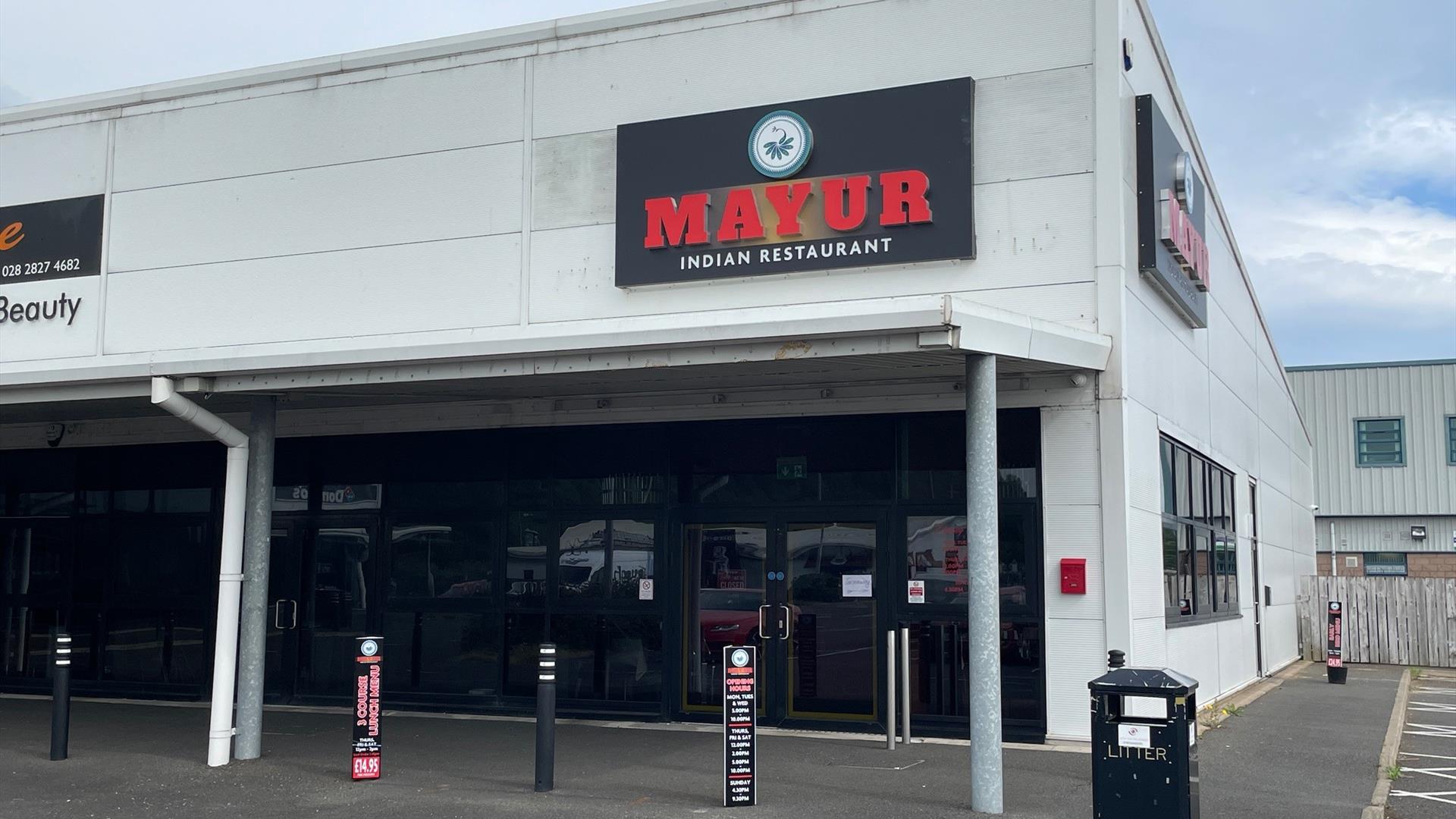 Exterior of Mayur Indian Restaurant in Larne with grey bulding and black windows / door