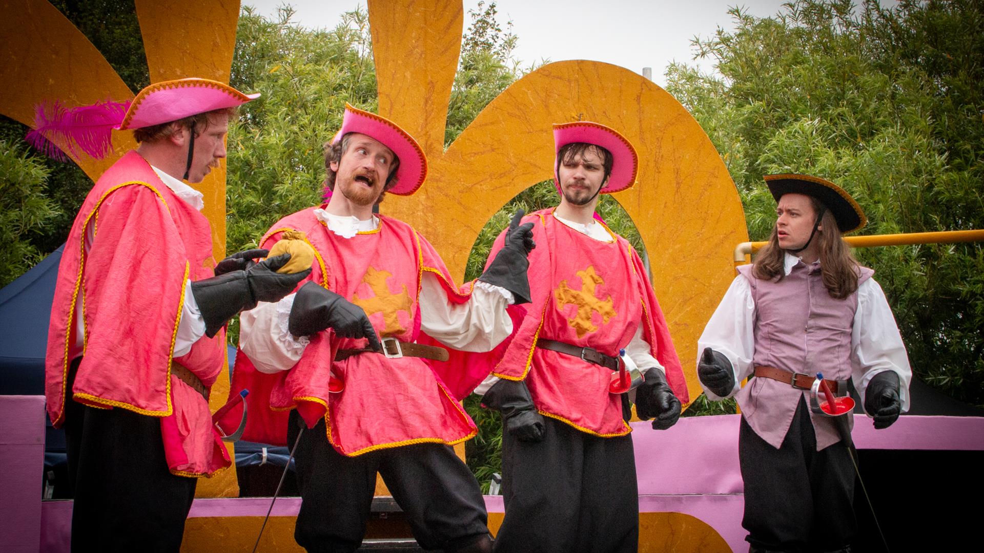 4 actors on outdoor stage performing.