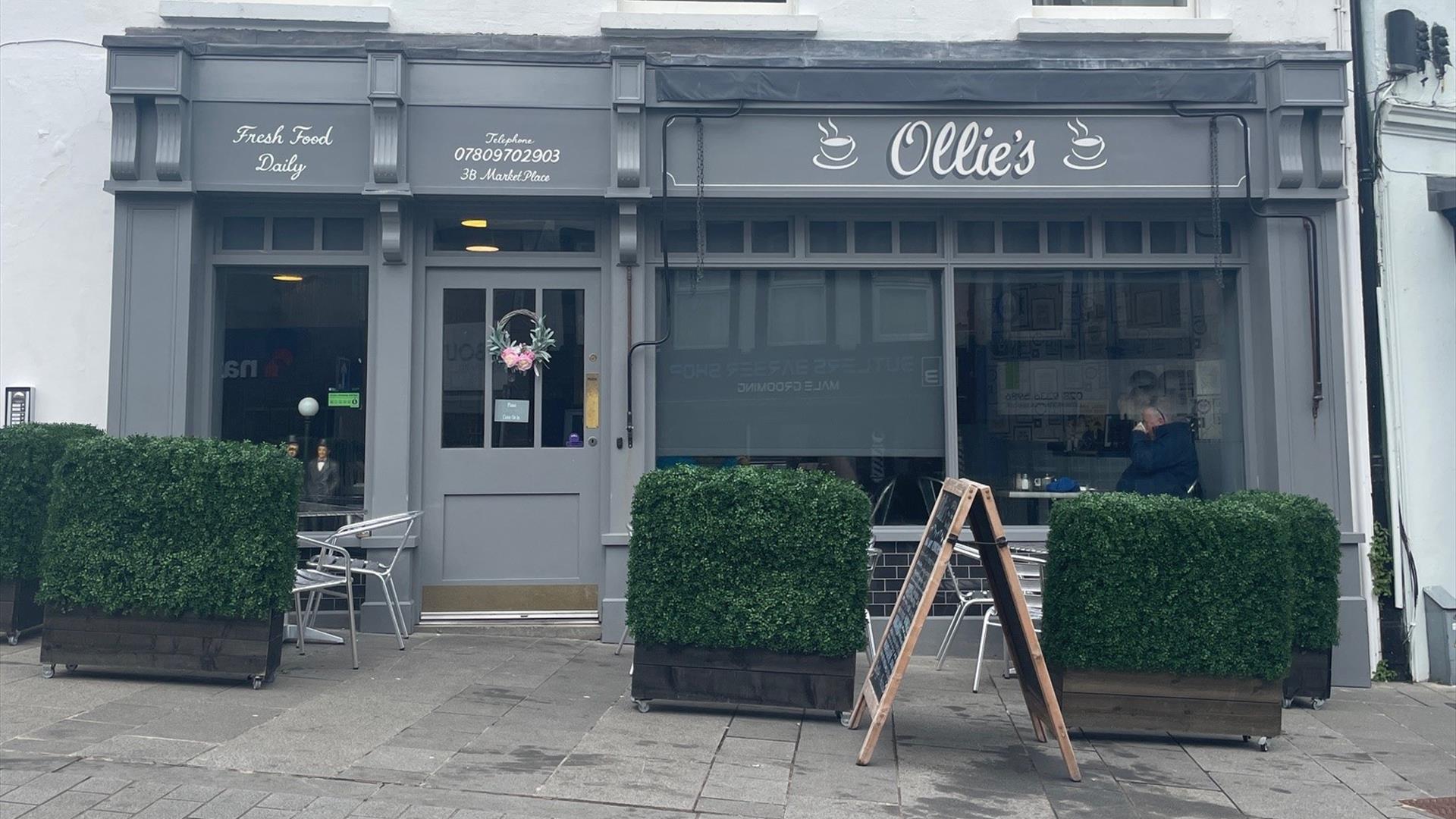 Exterior of Ollie's Bistro, Carrickfergus with grey exterior and outdoor seating area with hedge surround