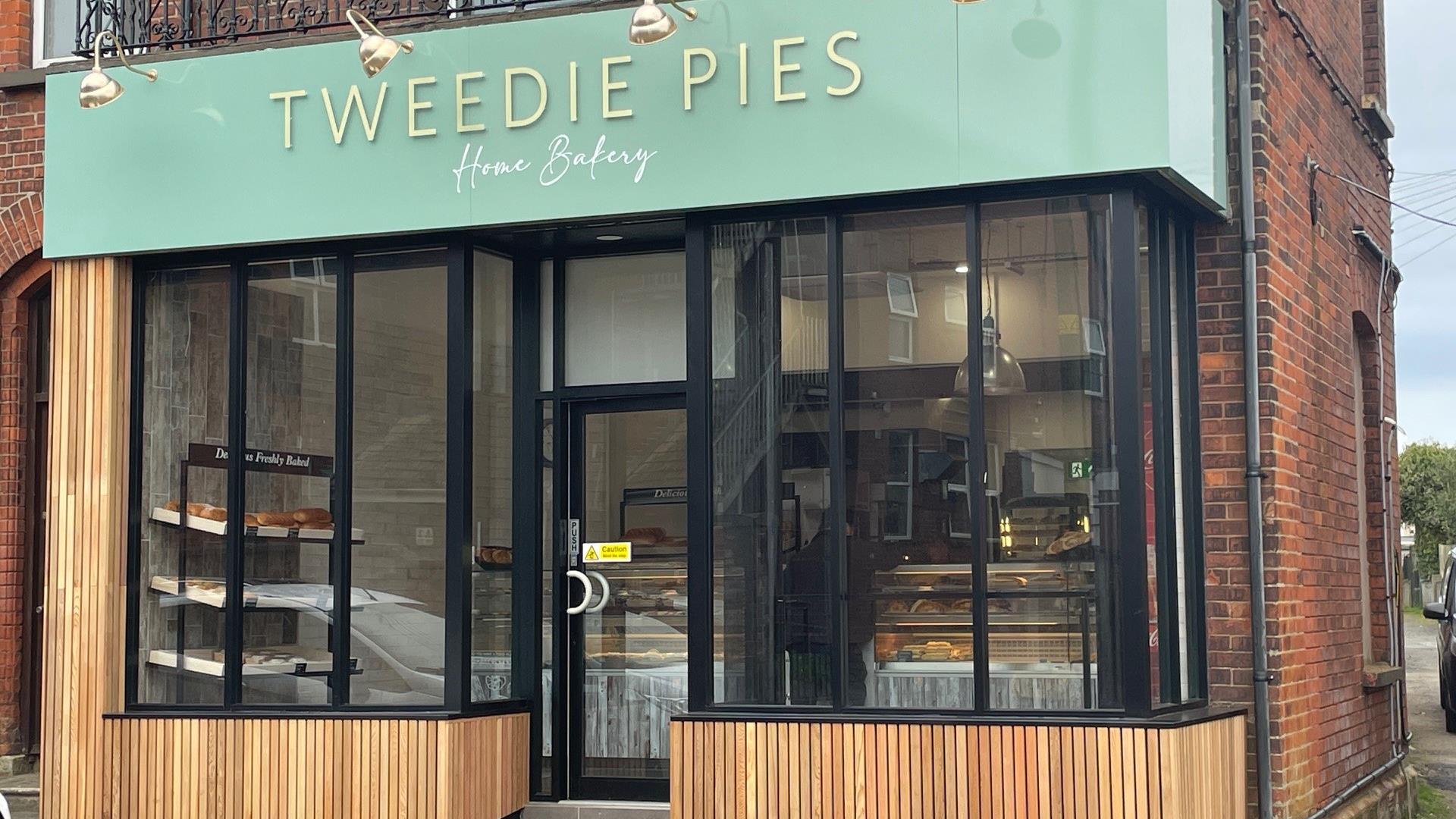 Exterior of Tweedie Pies Home Bakery with black framed glass, mint green sign and wooden panel trim