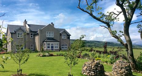 View of BallyCairn House from front garden. Situated on an elevated, picturesque location overlooking the Irish Sea with backdrop views of the Antrim