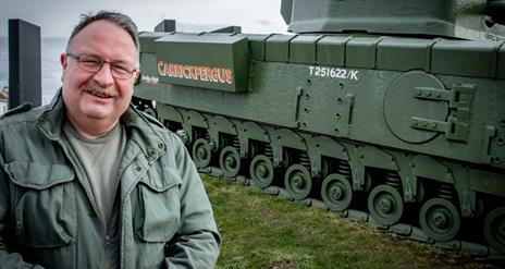 Adrian Hack, tour guide with Lead the Way Tours standing beside the Churchill Tank in Carrickfergus