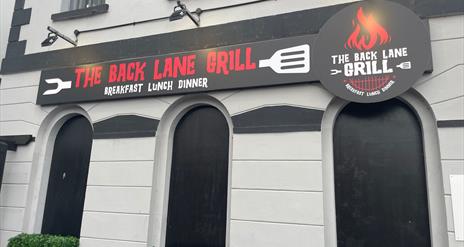 Exterior sign for The Back Lane Grill in red and white writing on black background