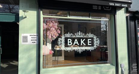 Exterior of Bake bakery in Larne painted light green with black canopy and word BAKE in large window