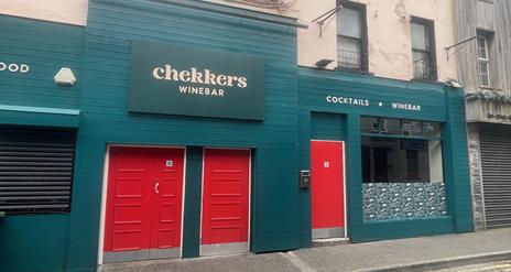 Teal Green exterior of Chekkers Wine Bar with red doors