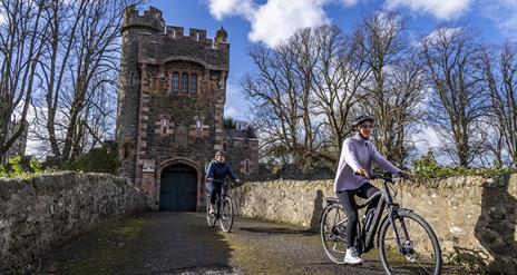 Two cyclists on the bridge that leads to the Barbican Gatelodge