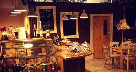 Serving counter in EJ's Country Kitchen in Hillstown, with drinks fridge to the front of the counter and display cases on the counter for scones, bake