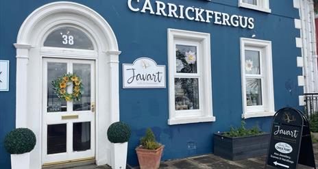 Blue and white exterior of Javart Gift Shop with potted plants