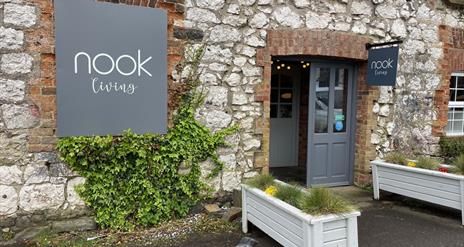 Brick exterior of Nook Living with grey signage and white planter