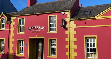 Pink and yellow exterior of Ownies Bar in Carrickfergus