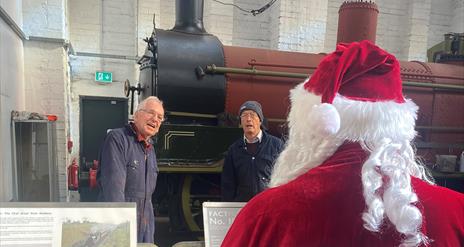 Train with engineers in front of it with Santa looking at them
