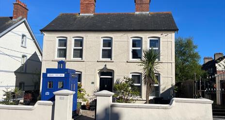 White exterior of Sergeants House with old style blue police box as feature in garden