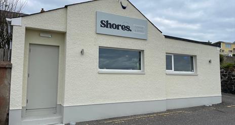 White exterior of Shores. Whitehead with windows facing onto Whitehead promenade.