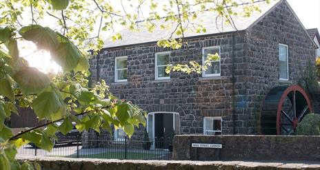 Stone Flax Mill restored self catering - black stone building with water wheel at side of house