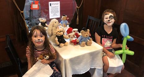 Two little girls sitting at a Teddy Bears Picnic on a train in Whitehead Railway Museum