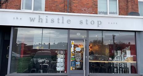 Exterior of the Whistle Stop cafe building painted grey and black with large signage