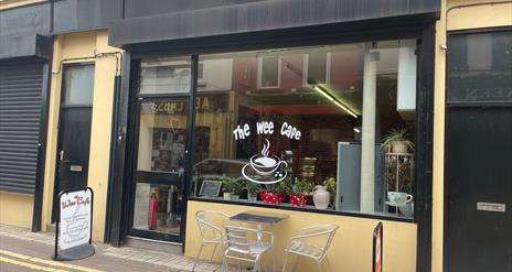 Yellow and Black exterior of the Wee Cafe Larne with name on window and silver outdoor seats