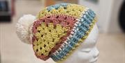 Crochet hat in  multi colours on headstand.